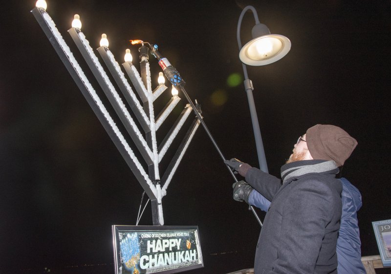 Rabbi Sholom Vogel helps light the menorah on the first night of Chanukah.